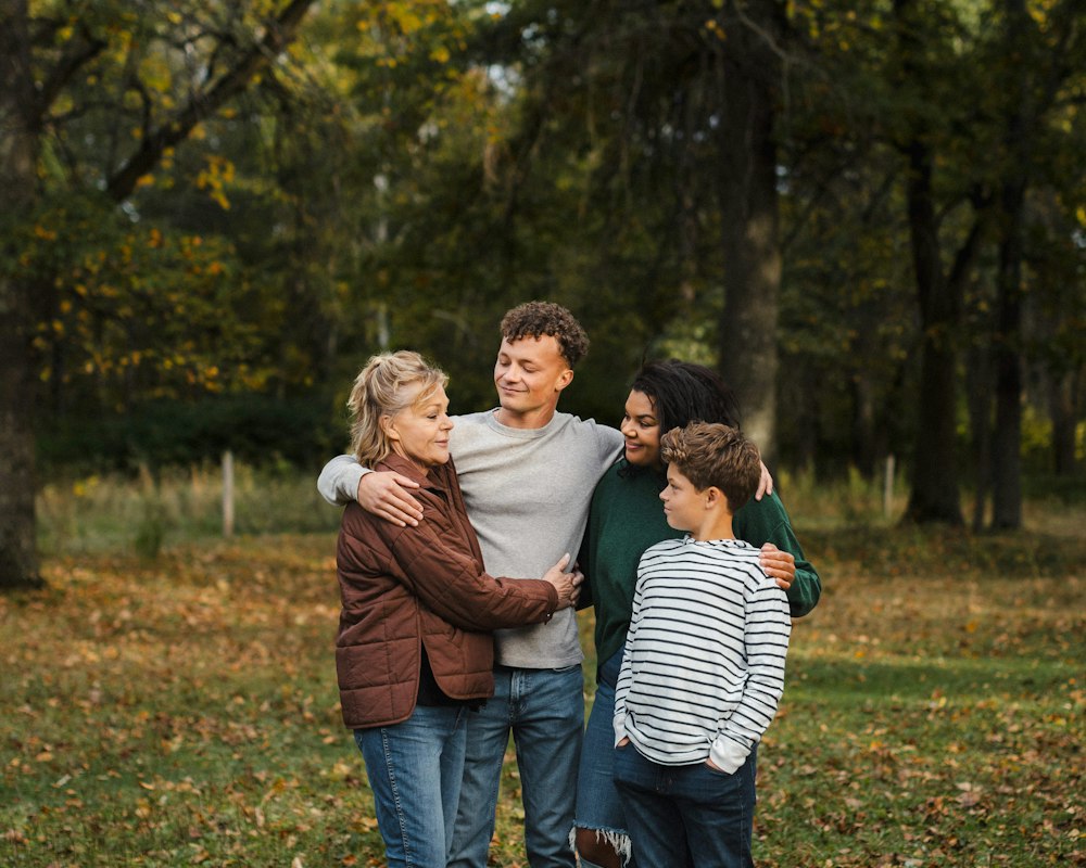 A smiling family of four standing together outdoors in autumn