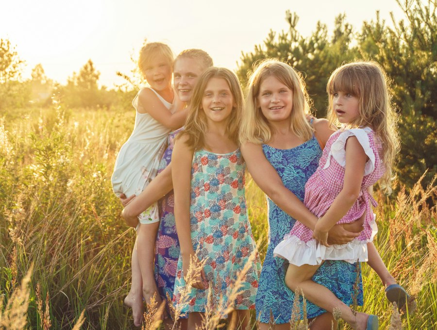 Mother and daughters in summer dresses in a sunlit field
