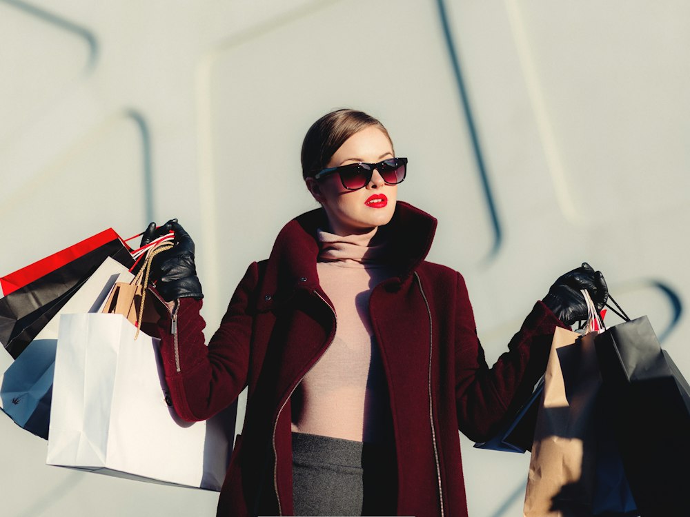 Stylish woman in a burgundy coat carrying shopping bags
